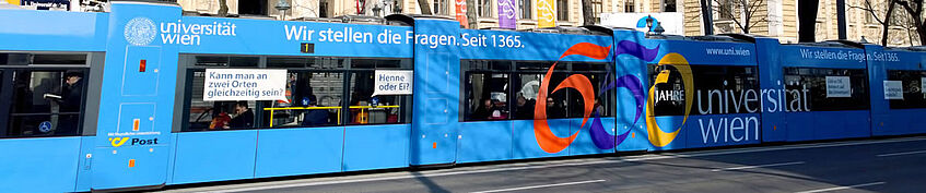 Blaue Straßenbahn mit der Aufschrift: Wir stellen die Fragen. Seit 1365. 650 Jahre Universität Wien