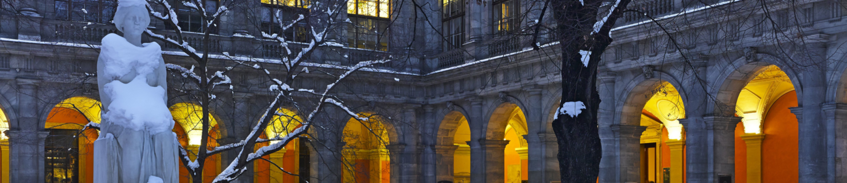 Arkadenhof der Universität Wien schneebedeckt und beleuchtet (in der Nacht)